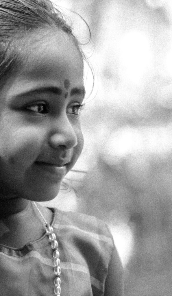 Black and white portrait of a smiling young girl with a traditional bindi.